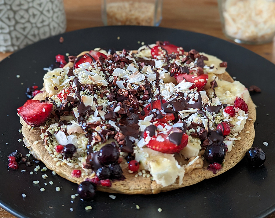 Vollkorn Pancake mit Erdnussmus, Banane, Kakaonibs, Beerenmix, 100% Schokolade, Kokoschips und Hanfsamen